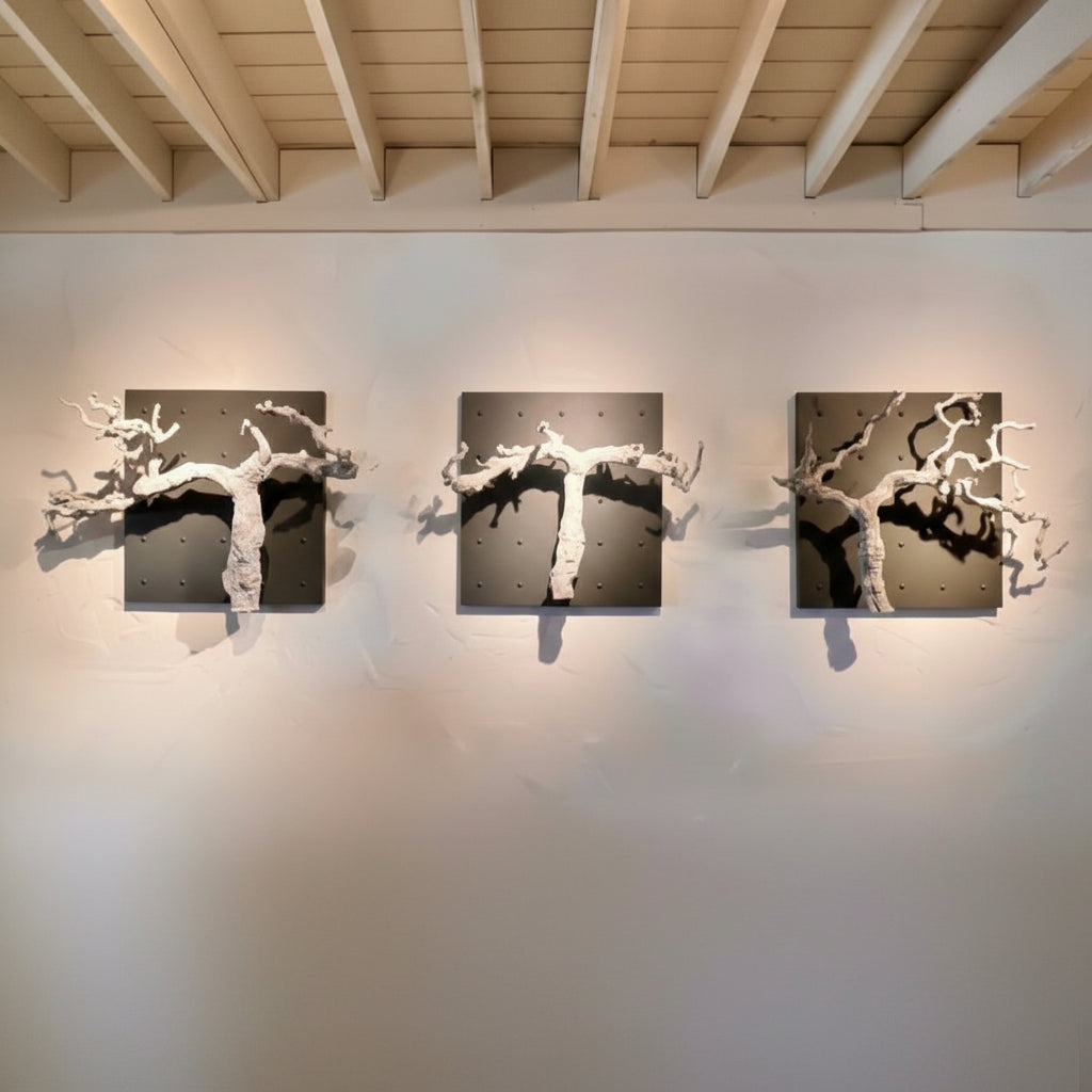 Three bleached grapevines on Curator Wall Panels on a white wall with wooden ceiling beams.
