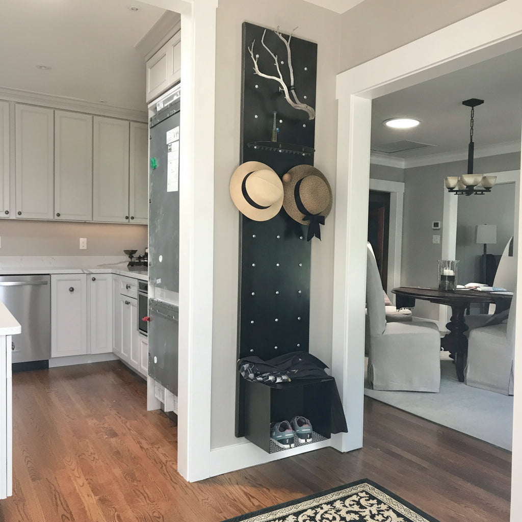 Modern interior with a tall black Curator Wall Panel coat rack holding hats and shoes, next to a kitchen.