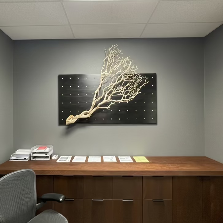 Modern office interior with a desk, chair, and Manzanita branch on decorative Curator Wall Panel wall art.
