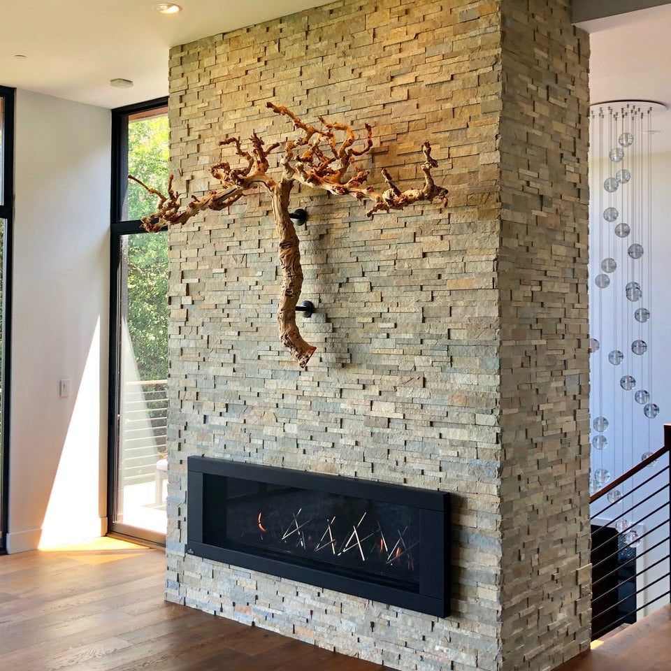 Modern stone fireplace with decorative branch on two Curator Wall Mounts above it in a living room.

